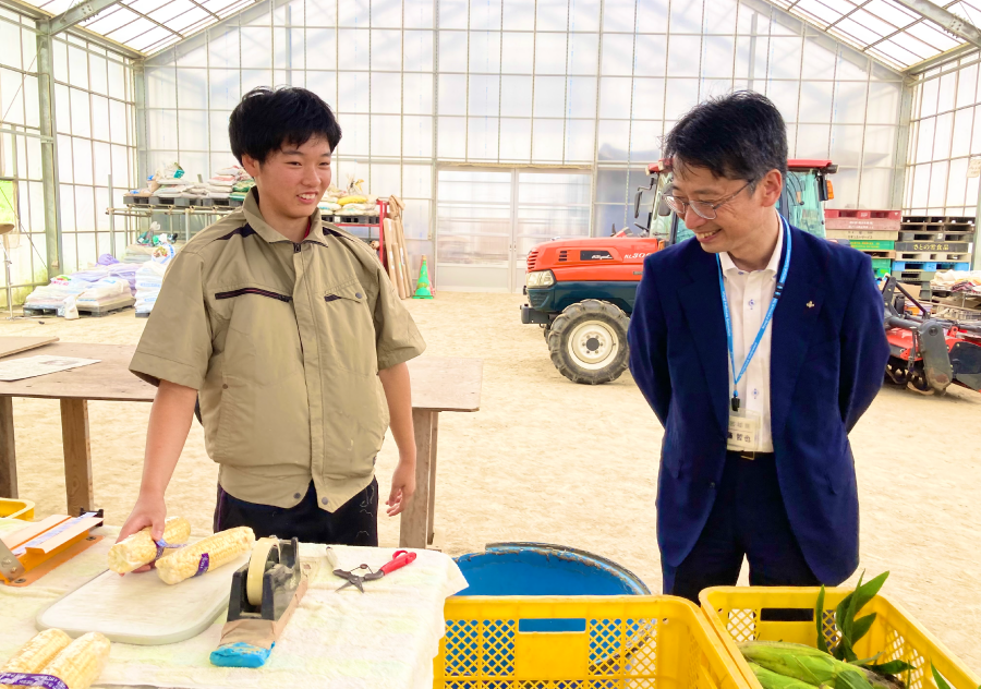 ＜収穫したトウモロコシをパッケージする菅野選手と作業を見守る伊藤副知事＞